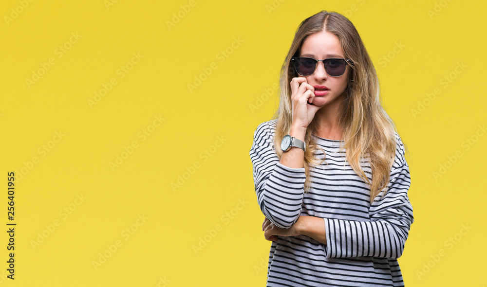 Young beautiful blonde woman wearing sunglasses over isolated background looking stressed and nervous with hands on mouth biting nails. Anxiety problem. - obrazy, fototapety, plakaty 
