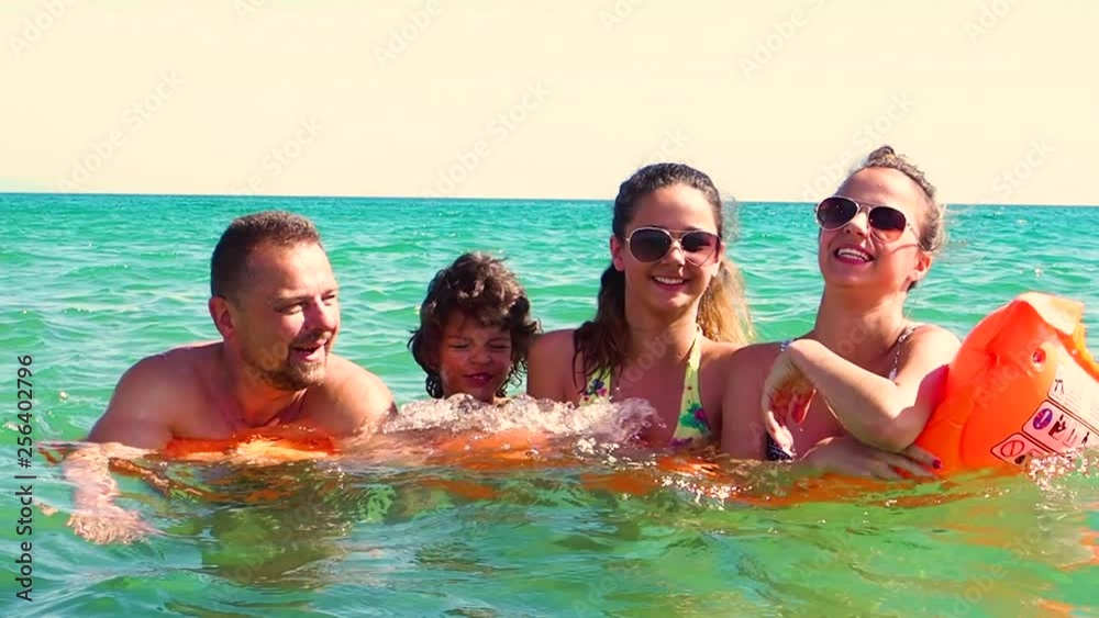Happy family of four in vacation at sea shore. Happy family with yellow mattress bathes in sea. happy mum daddy and two children play in water. Slow Motion Happy family of four in vacation at sea shore. Happy family with yellow mattress bathes in sea. happy mum daddy and two children play in water. Slow Motion