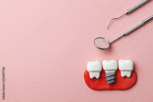Healthy white teeth and implants  on pink background and dentist tools mirror, hook. Copy space for text. © adragan