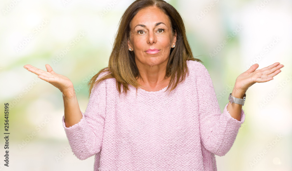 Beautiful middle age adult woman wearing winter sweater over isolated background clueless and confused expression with arms and hands raised. Doubt concept. Beautiful middle age adult woman wearing winter sweater over isolated background clueless and confused expression with arms and hands raised. Doubt concept.