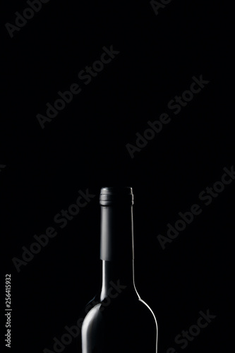 Glass wine bottle in darkness isolated on black