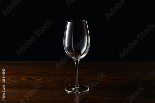 Empty wine glass on wooden surface isolated on black
