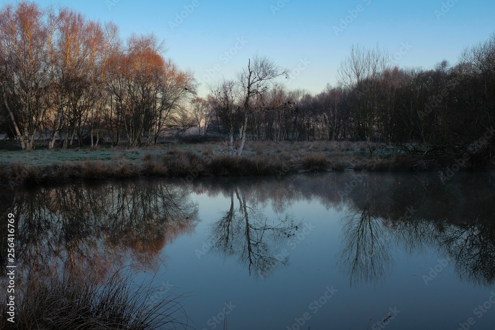 first light of sunrise reflected in a bedfordshire lake