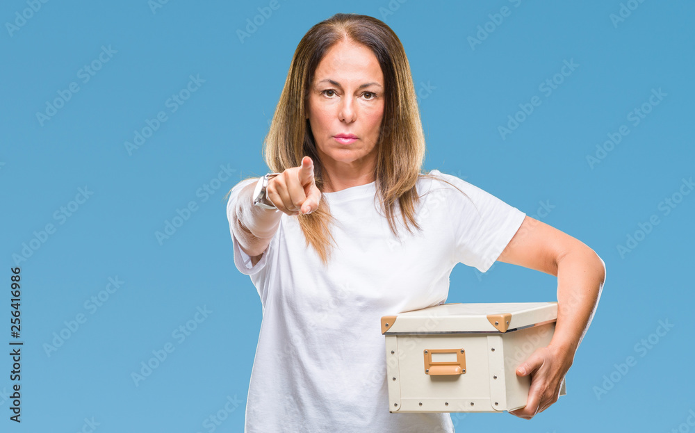 Middle age hispanic woman moving holding packing box over isolated background pointing with finger to the camera and to you, hand sign, positive and confident gesture from the front Middle age hispanic woman moving holding packing box over isolated background pointing with finger to the camera and to you, hand sign, positive and confident gesture from the front