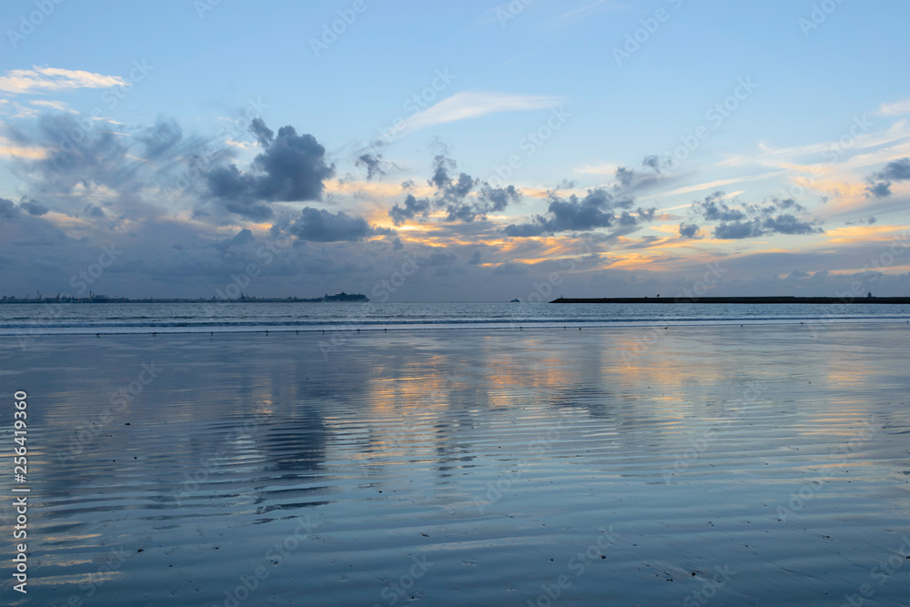 Atardecer en playa mostrando todos los reflejos del cielo sobre la arena mojada