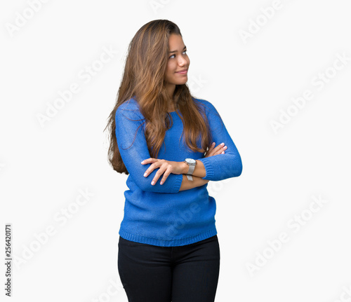 Young beautiful brunette woman wearing blue sweater over isolated background smiling looking to the side with arms crossed convinced and confident