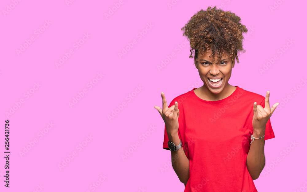 Beautiful young african american woman over isolated background shouting with crazy expression doing rock symbol with hands up. Music star. Heavy concept. Beautiful young african american woman over isolated background shouting with crazy expression doing rock symbol with hands up. Music star. Heavy concept.