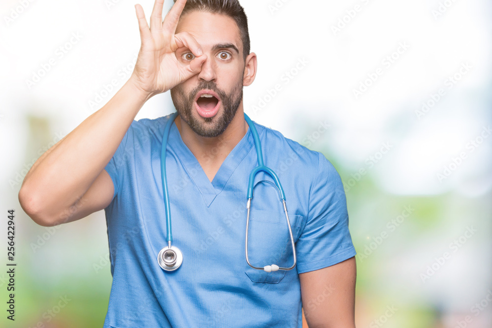 Handsome young doctor surgeon man over isolated background doing ok gesture shocked with surprised face, eye looking through fingers. Unbelieving expression. Handsome young doctor surgeon man over isolated background doing ok gesture shocked with surprised face, eye looking through fingers. Unbelieving expression.