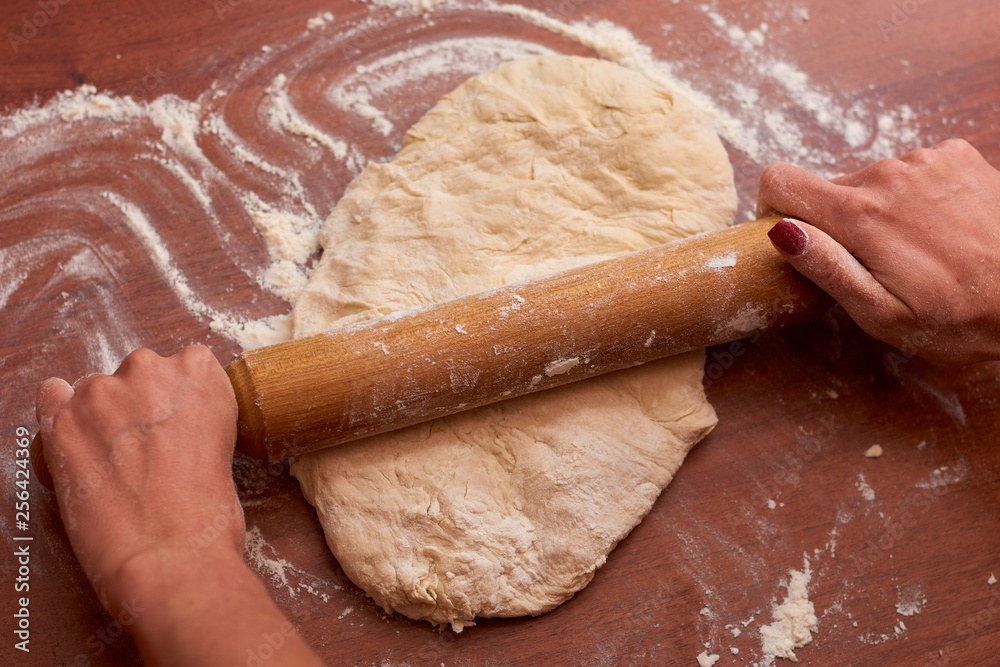 Dough for pizza. Rolling pin and dough on wooden background Dough for pizza. Rolling pin and dough on wooden background