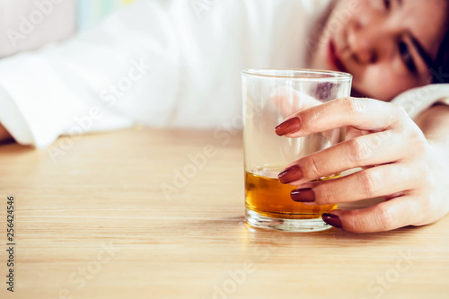 drunk woman hand holding glass of alcohol and sleeping on table 