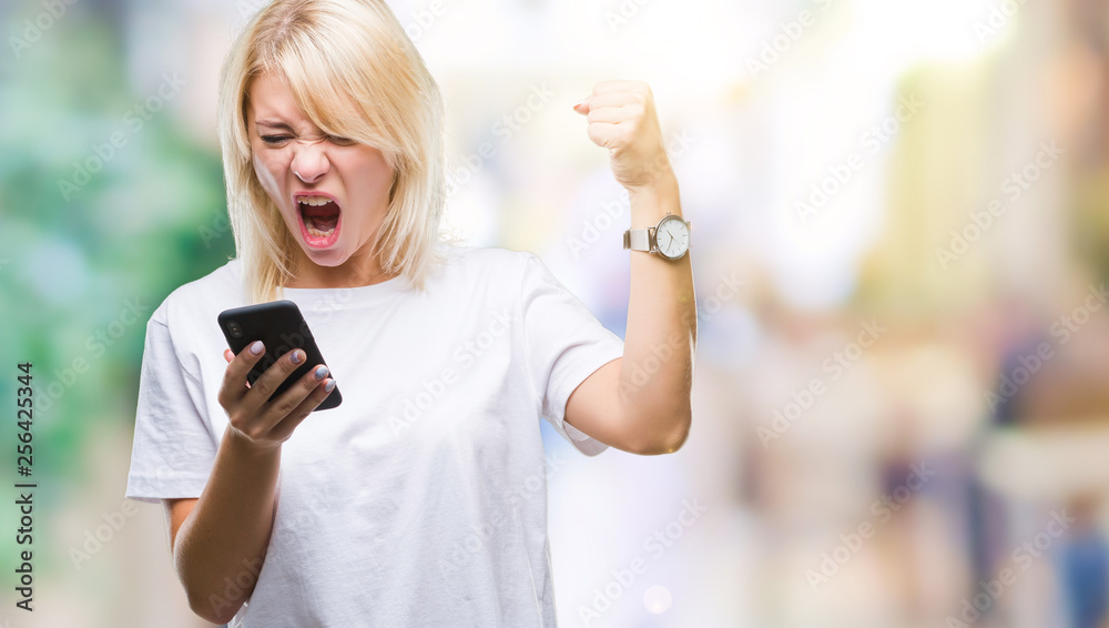 Young beautiful blonde woman using smartphone over isolated background annoyed and frustrated shouting with anger, crazy and yelling with raised hand, anger concept