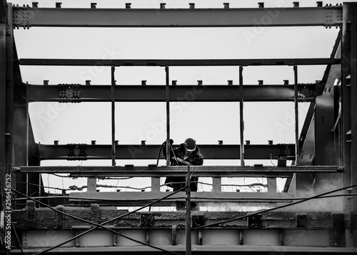 On a black and white photo of the Builder at work to remove dust from the metal frame 