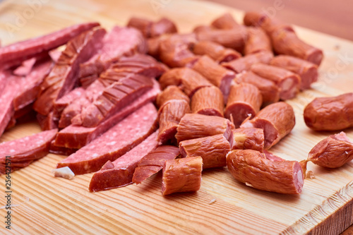 A variety of processed cold meat products, on a wooden cutting board