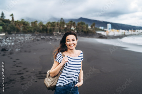 Pretty brunette girl walking on the black sand beach.
