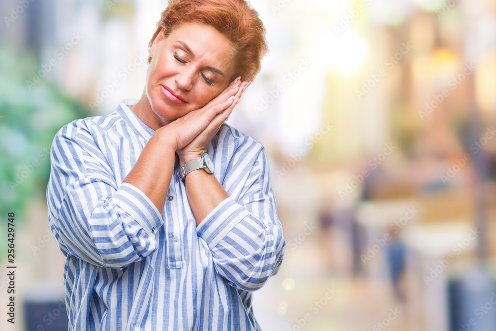 Atrractive senior caucasian redhead woman over isolated background sleeping tired dreaming and posing with hands together while smiling with closed eyes.