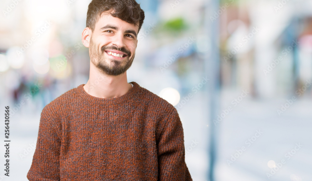Young handsome man wearing winter sweater over isolated background looking away to side with smile on face, natural expression. Laughing confident. Young handsome man wearing winter sweater over isolated background looking away to side with smile on face, natural expression. Laughing confident.