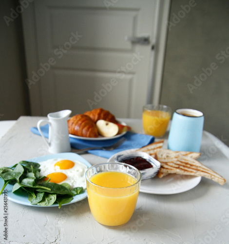 breakfast. side view. light background. scrambled eggs, orange juice, toast, jam, croissants, coffee, milk, morning, close up