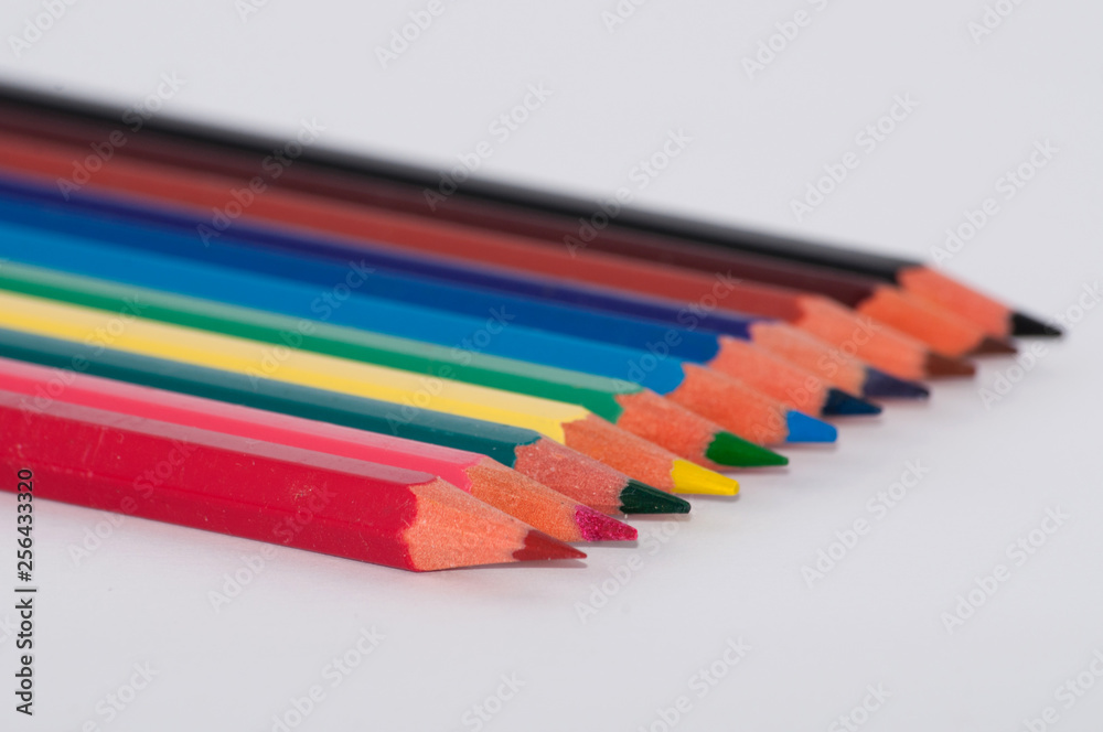 Fototapeta premium Many colored pencils on a white background close-up, macro, side view, with space for text.