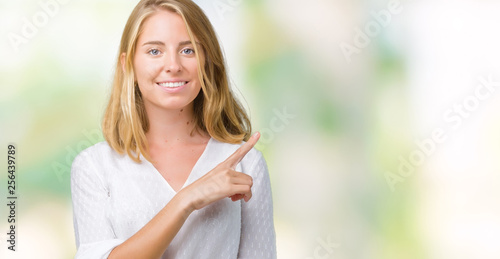 Beautiful young elegant woman over isolated background Pointing with hand finger to the side showing advertisement, serious and calm face © Krakenimages.com