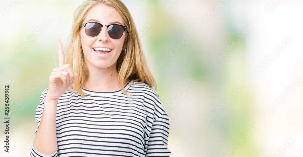 Beautiful young woman wearing sunglasses over isolated background pointing finger up with successful idea. Exited and happy. Number one. Beautiful young woman wearing sunglasses over isolated background pointing finger up with successful idea. Exited and happy. Number one.