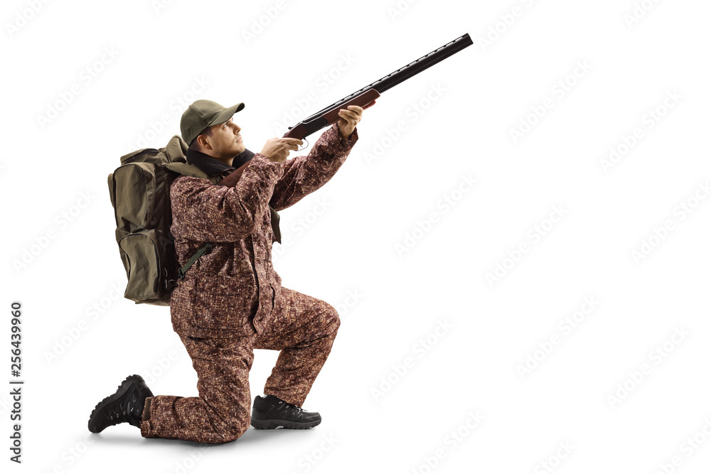 Man hunter in a uniform kneeling with a shotgun aiming up Man hunter in a uniform kneeling with a shotgun aiming up