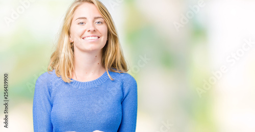 Beautiful young woman wearing blue sweater over isolated background Smiling with hands palms together receiving or giving gesture. Hold and protection © Krakenimages.com