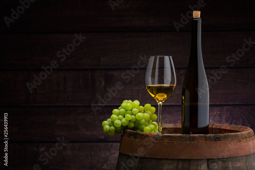 white wine bottle and wine glass on wodden barrel