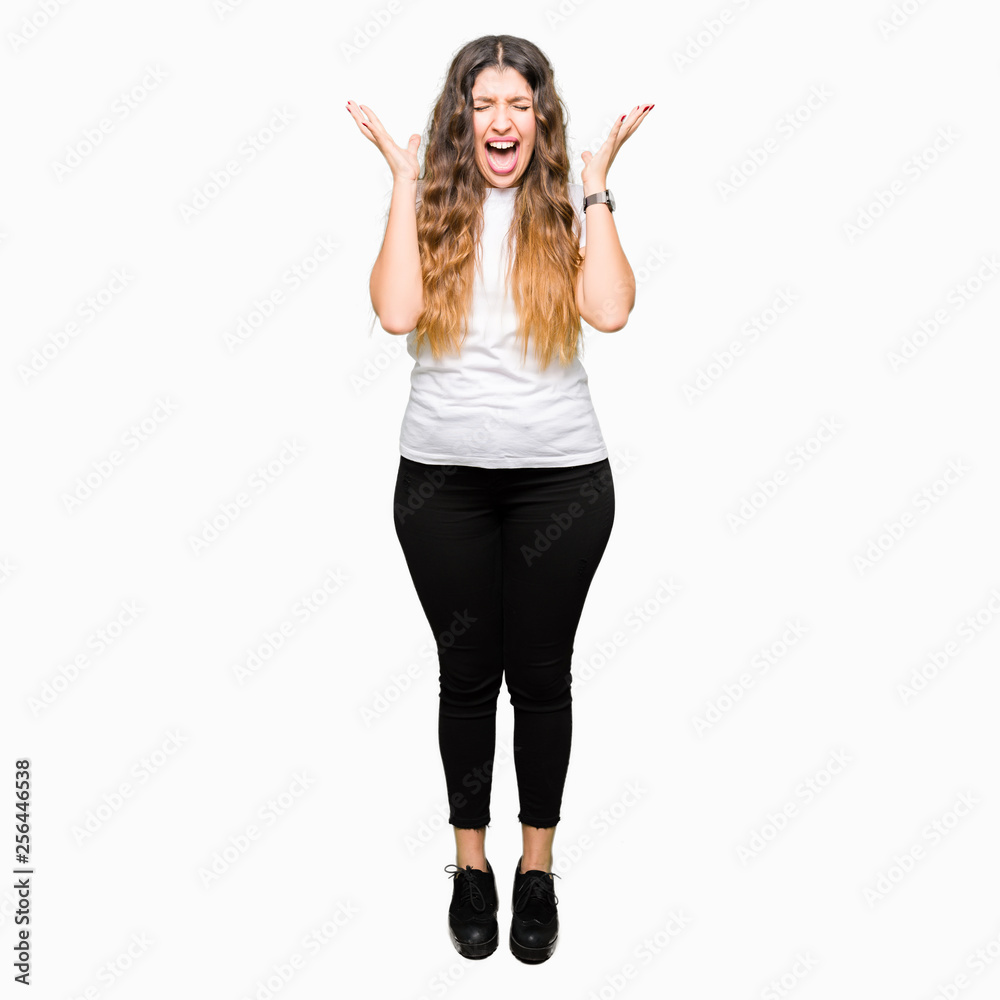 Young beautiful woman wearing casual white t-shirt celebrating mad and crazy for success with arms raised and closed eyes screaming excited. Winner concept Young beautiful woman wearing casual white t-shirt celebrating mad and crazy for success with arms raised and closed eyes screaming excited. Winner concept