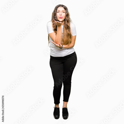 Young beautiful woman wearing casual white t-shirt looking at the camera blowing a kiss with hand on air being lovely and sexy. Love expression.