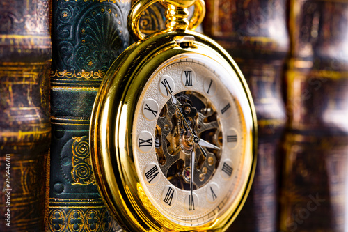 Antique clock on the background of vintage books. Mechanical clockwork on a chain.