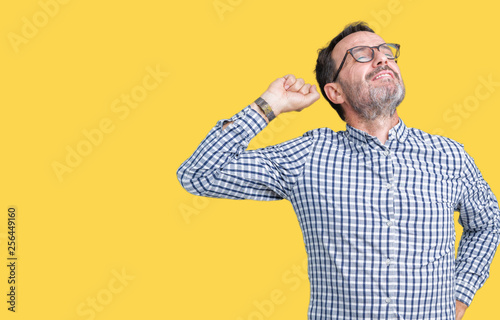 Handsome middle age elegant senior man wearing glasses over isolated background stretching back, tired and relaxed, sleepy and yawning for early morning