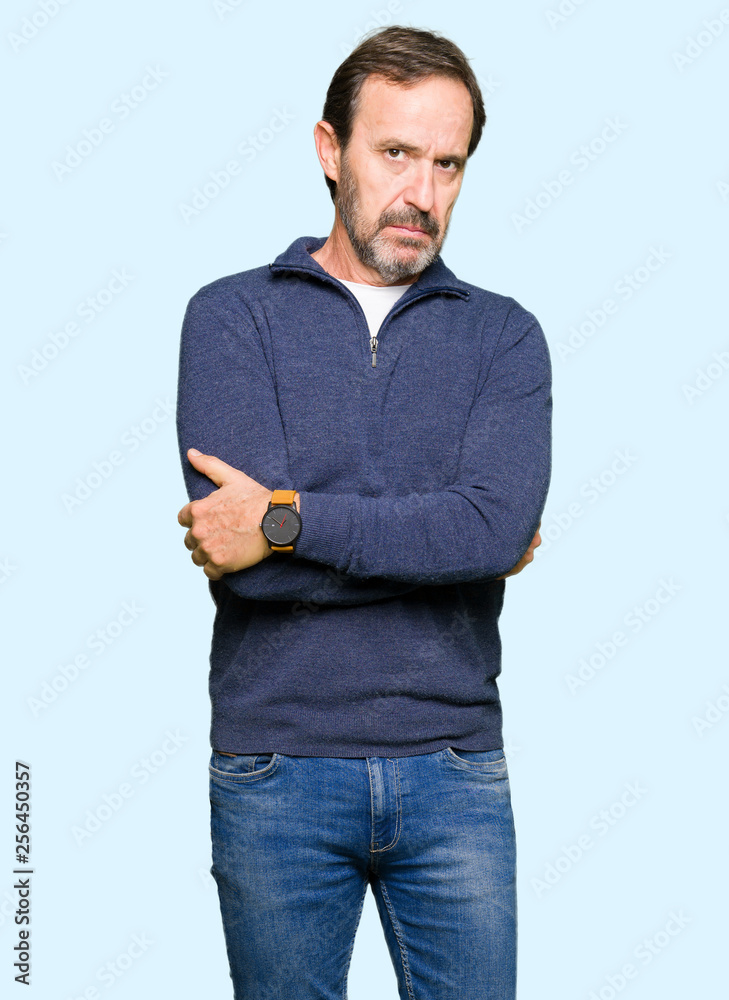 Middle age handsome man wearing a sweater skeptic and nervous, disapproving expression on face with crossed arms. Negative person.