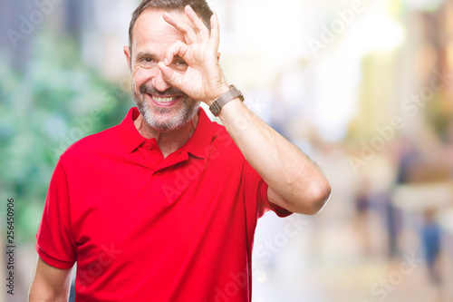 Middle age hoary senior man over isolated background doing ok gesture with hand smiling, eye looking through fingers with happy face.