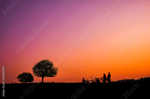 Silhouette of two trees and tourists who ride the bike at sunset at Thung Kraang, Chaiyaphum Province, Thailand © subinpumsom
