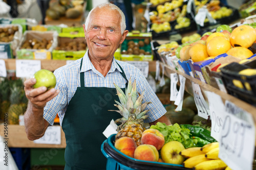 Elderly salesman working in greengrocery