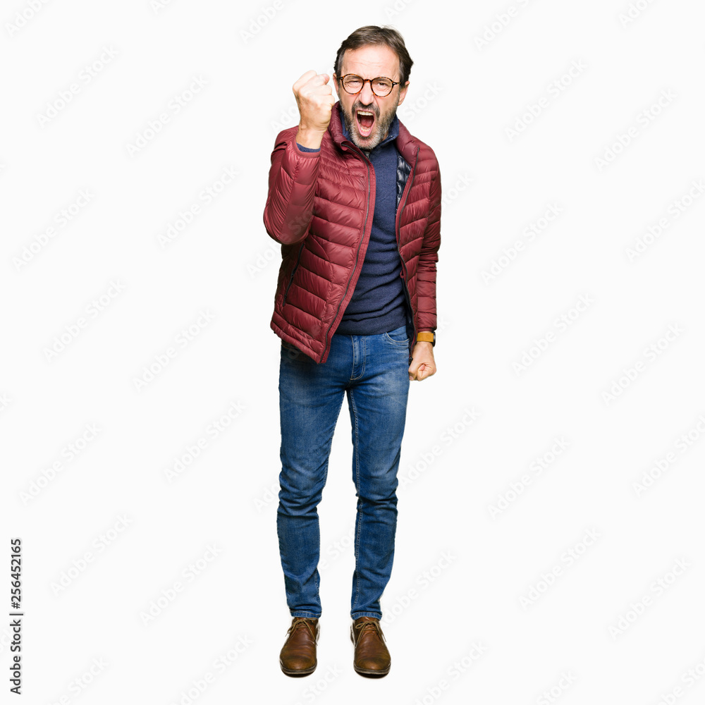 Middle age handsome man wearing glasses and winter coat angry and mad raising fist frustrated and furious while shouting with anger. Rage and aggressive concept. Middle age handsome man wearing glasses and winter coat angry and mad raising fist frustrated and furious while shouting with anger. Rage and aggressive concept.