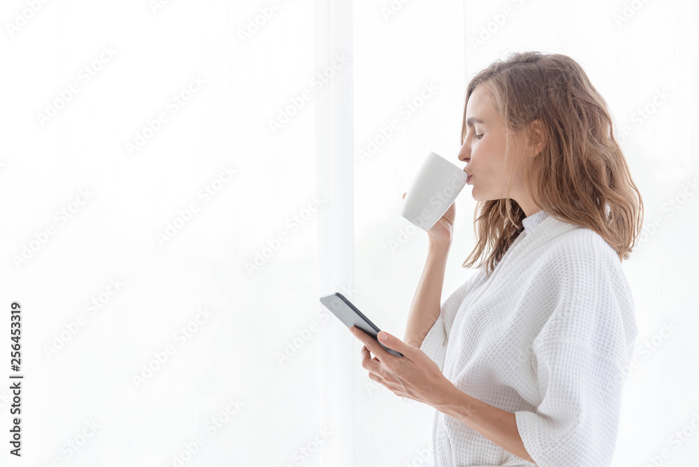 Young beautiful women having a coffee after wake up with checking mail from mobile phone in weekend morning. Young beautiful women having a coffee after wake up with checking mail from mobile phone in weekend morning.