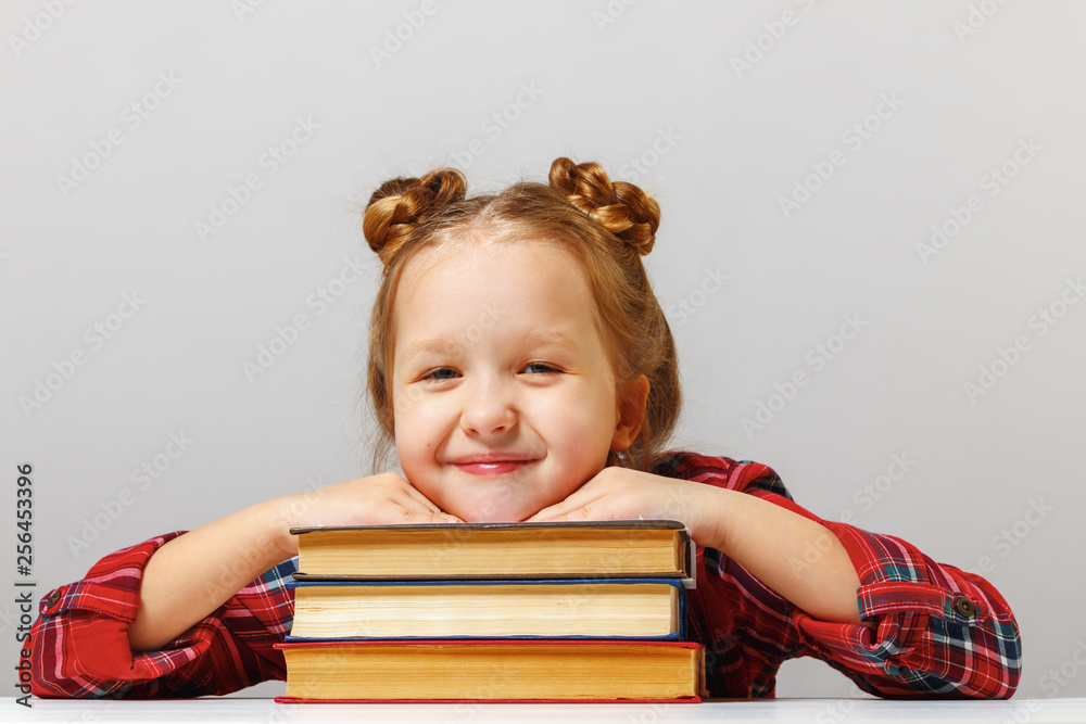 Cute little child girl sitting at the table, leaning on thick books. Education concept. Cute little child girl sitting at the table, leaning on thick books. Education concept.