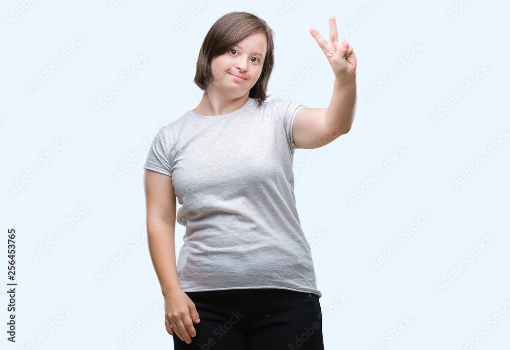 Young adult woman with down syndrome over isolated background smiling with happy face winking at the camera doing victory sign. Number two. Young adult woman with down syndrome over isolated background smiling with happy face winking at the camera doing victory sign. Number two.