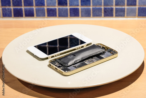 Φωτογραφία Selective focus of  inside a damaged broken and bloated mobile phone battery with loose display beside