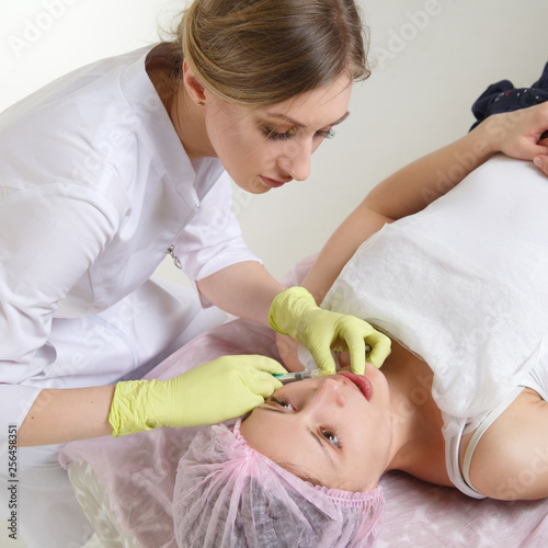 The doctor beautician makes the patient an injection.