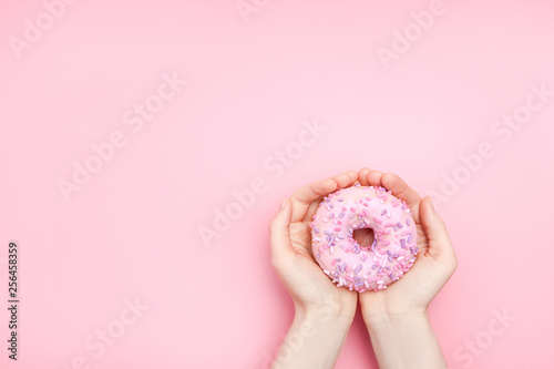 girl holding a glazed pink donut on a pink monochromatic background