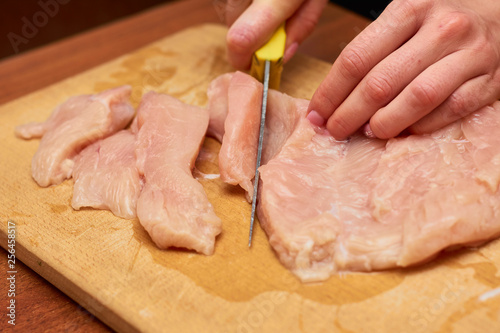 hands cutting raw meat