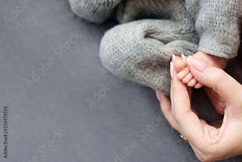 Feet of a newborn baby, toes in the hands of mom, hands and nails of a child, the first days of life after birth, scaly skin