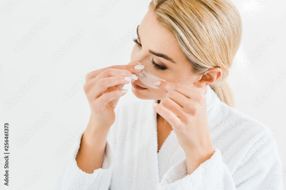 blonde and attractive woman in white bathrobe applying eye patches in bathroom blonde and attractive woman in white bathrobe applying eye patches in bathroom