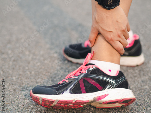 Athlete woman has ankle injury, sprained leg during running training. sport concept.