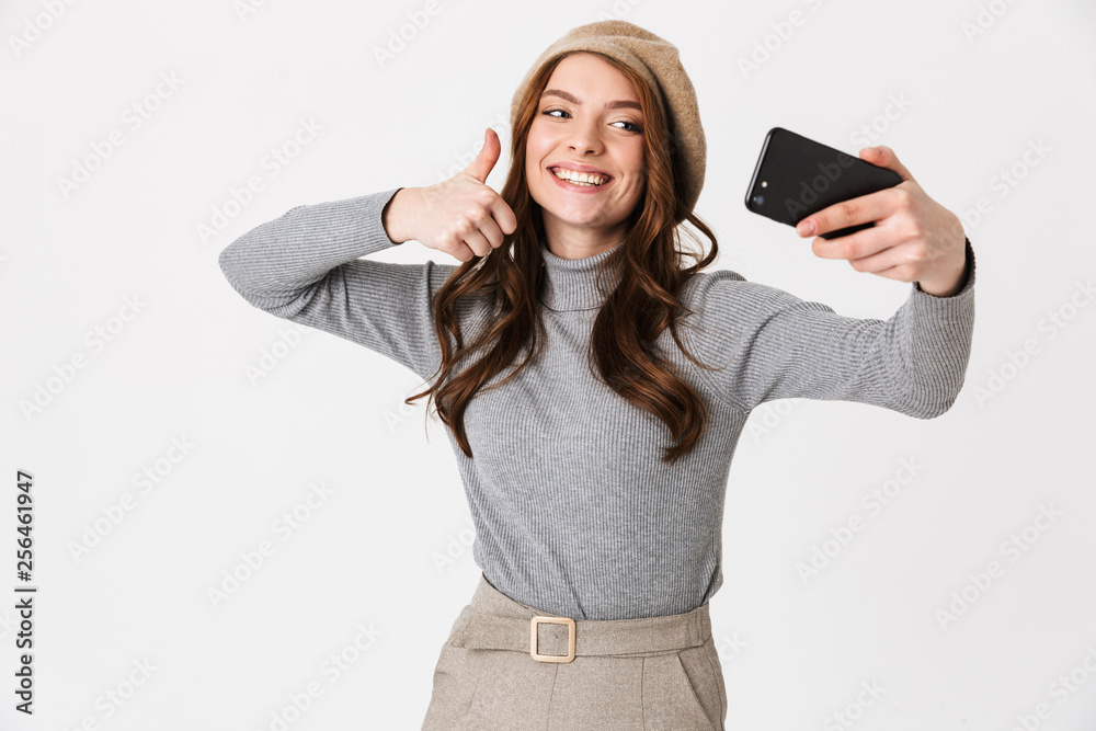 Naklejka premium Happy woman isolated over white wall background take selfie by mobile phone.