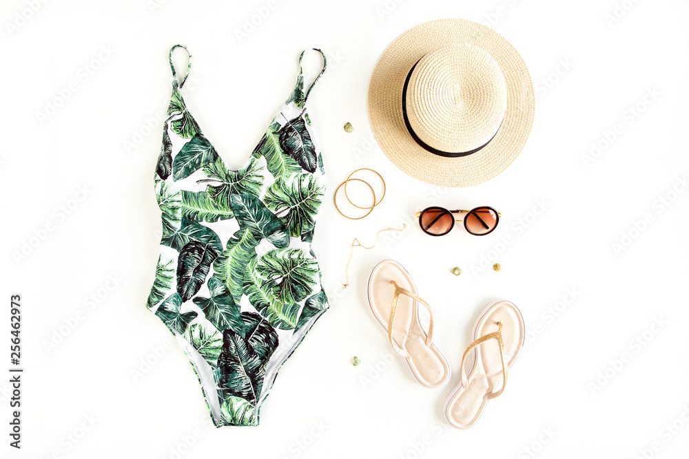 Woman's beach accessories: swimsuit with tropical print, rattan bag, straw hat on white background. Summer background. Flat lay, top view. - obrazy, fototapety, plakaty 