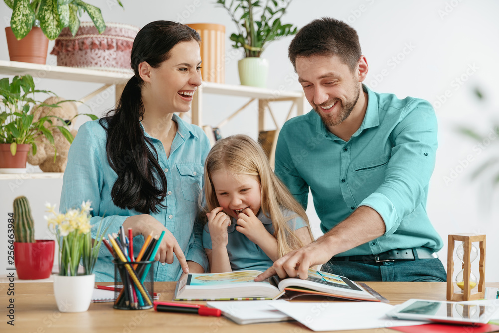Father, mother and their daughter are smiling while spending time together. A day with family. Young happy couple with child are studying with the book. Education, studying and knowledge sharing Father, mother and their daughter are smiling while spending time together. A day with family. Young happy couple with child are studying with the book. Education, studying and knowledge sharing