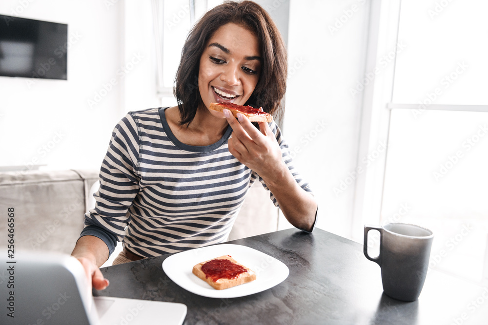 Smiling young african woman having breakfast